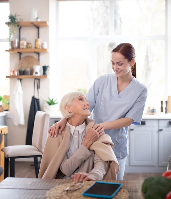 Vertrauensvolles Gespraech zwischen Betreuerin und Seniorin in einem Westerwaelder Wohnzimmer